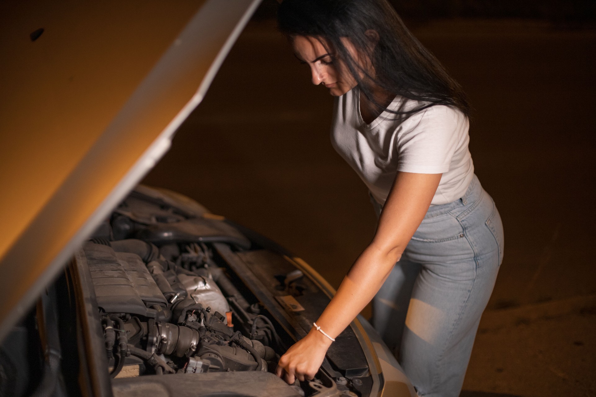 Young woman checking  her broken car night time